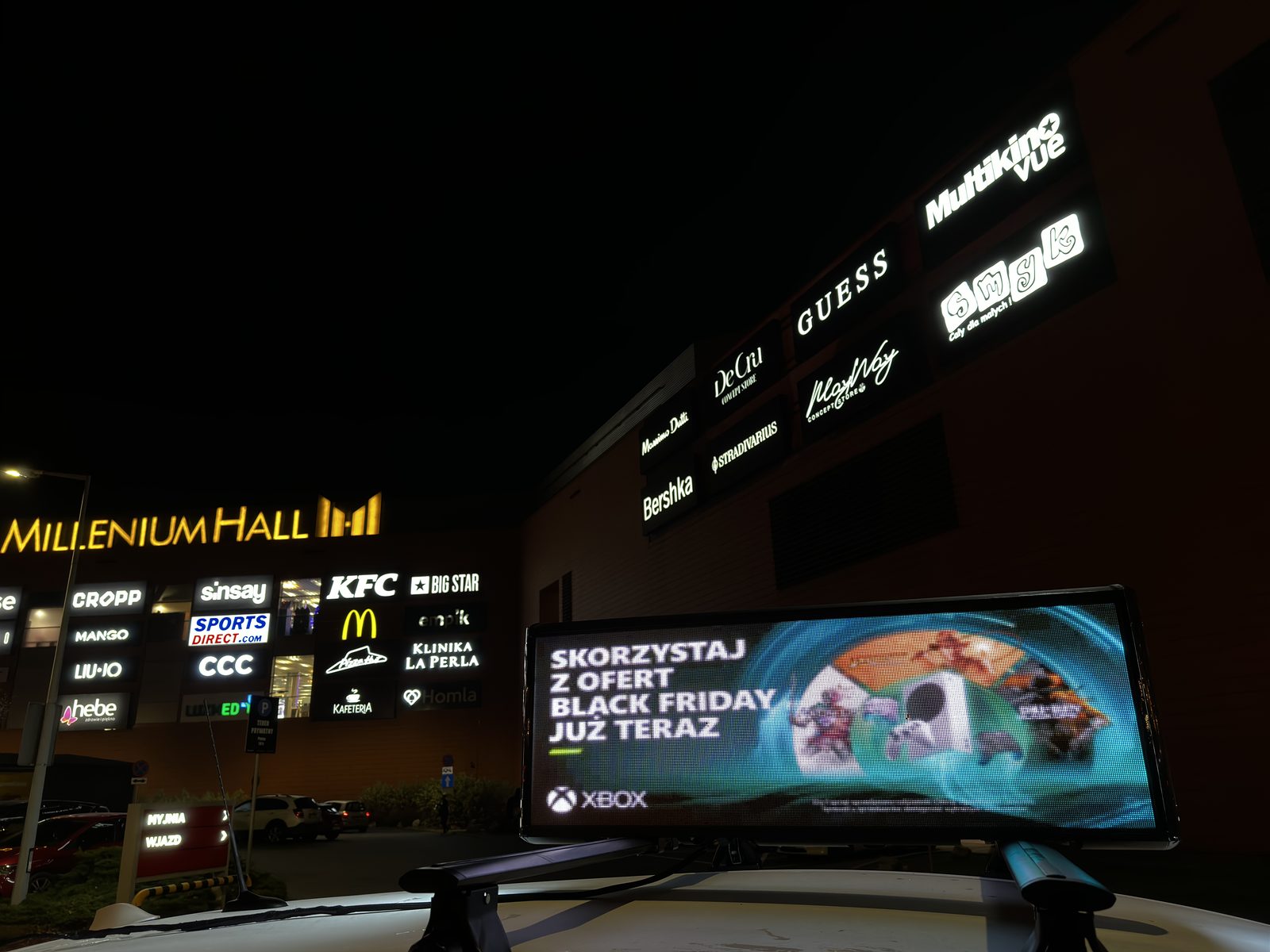 Ekran LED na taksówce przed Millenium Hall nocą
