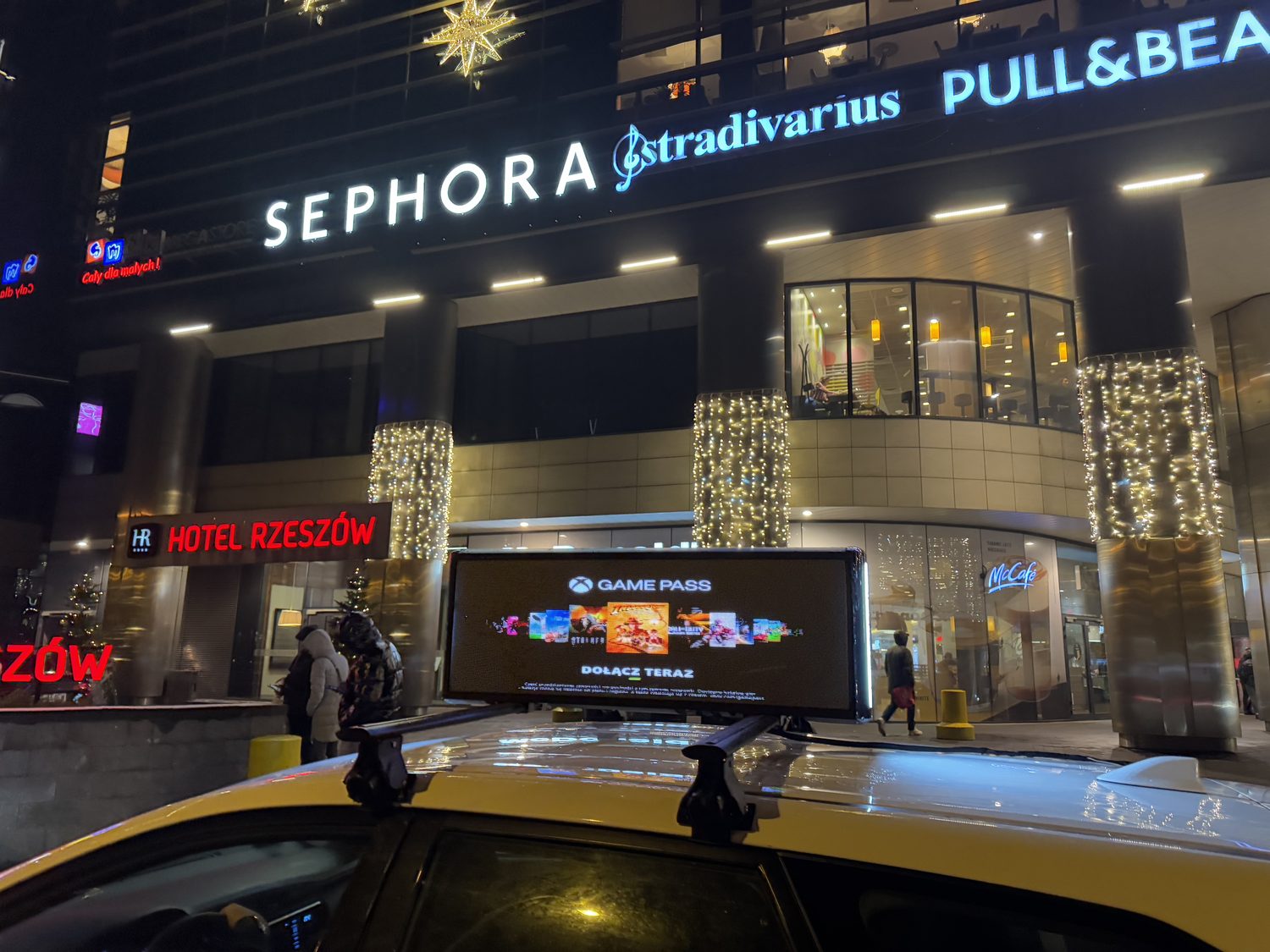 Taxi z ekranem LED przy wejściu do galerii handlowej